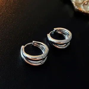 Detailed close-up of silver multilayer C-shaped earrings on a black textured background
