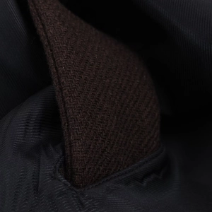 Close-up of dark brown wool fabric texture and navy blue inner lining of the short coat