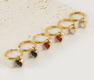 Three pairs of gold hoop earrings with black, red and white heart-shaped zircon pendants