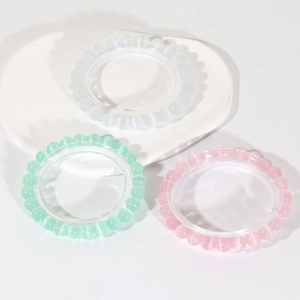 Three cat-eye stone beaded bracelets in white, mint green and pink on a white tray