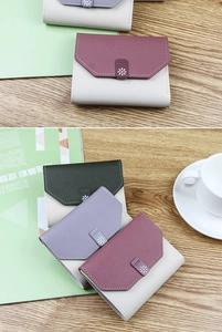 Close-up of color-block tri-fold wallets with daisy metal buckle on a wooden table
