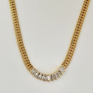 Close-up of golden woven chain necklace with thirteen baguette-cut cubic zirconia stones