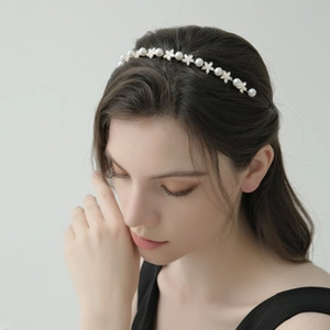 Detailed view of elegant headband featuring white pearls and metal flower motifs