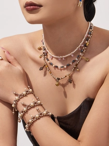 Detail view of multi-layer pearl necklace and bracelet with ethnic Hamsa Hand charms