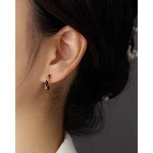 Spiral black and gold enamel s925 silver hoop earrings shown on a model's ear