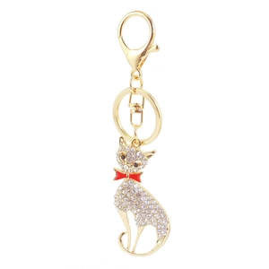Creative golden fox keychain with sparkling rhinestones and a red bow on white background
