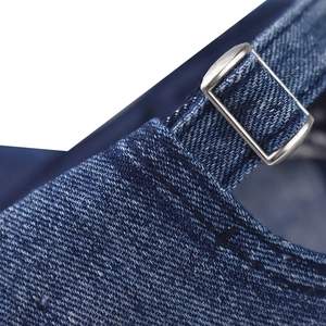 Detail of blue denim baseball cap showing silver metal buckle and adjustable strap