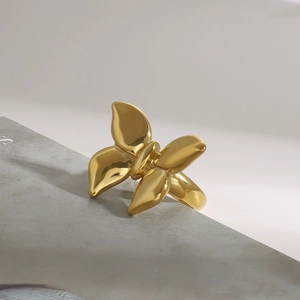 Detail shot of a golden stainless steel butterfly ring on a minimalist stone display