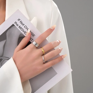 Close-up of stacked lava texture rings in silver and gold on a model's hand