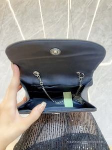 Macro view of dark chain flap bag interior with silver magnetic buckle and card slot