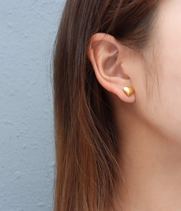 Close-up of a minimalist gold heart stud earring made of titanium steel on an ear