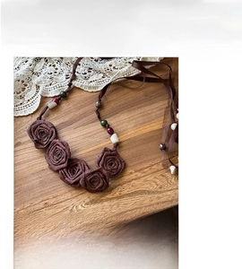 Detailed view of handmade fabric rose waist chain with colorful beads and dark brown ribbon