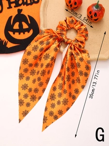 Detail view of orange Halloween hair scrunchie with spider web print and long ribbons