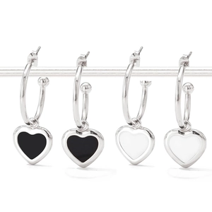 Detailed view of silver heart hoop earrings with black and white enamel pendants
