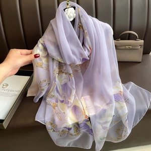Detail of lavender silk shawl with floral pattern draped on a leather background