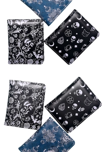 Detailed view of Gothic skulls and floral prints on compact zip wallets set against white background