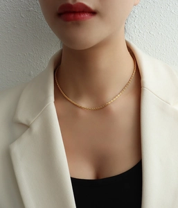Close-up of minimalist gold plated shimmering necklace on a female model with white jacket