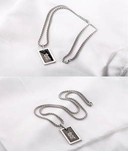 Détail du pendentif carré noir avec motif de dragon argenté sur une chaîne box