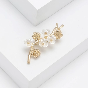Detailed view of elegant gold branch brooch with white pearlescent flower petals