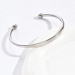 Elegant silver stainless steel C-shaped open bangle with polished bead ends on white porcelain