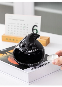 Placing a tealight candle into a black ceramic ghost holder with stitched mouth detail