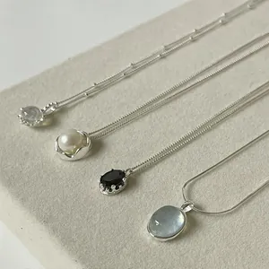Detail showing four silver pendant necklaces with pearls and faceted gemstones on display