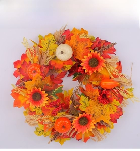Detail of harvest wreath with maple leaves, sunflowers and pumpkins on white background