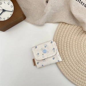 Close-up of a small floral storage pouch featuring a button closure and brand tag