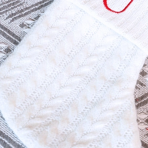 Détail d'une chaussette de Noël en maille blanche avec broderie de lettres rouges