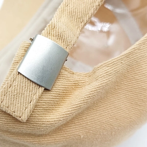 Detailed macro view of the adjustable silver metal buckle on a canvas baseball cap