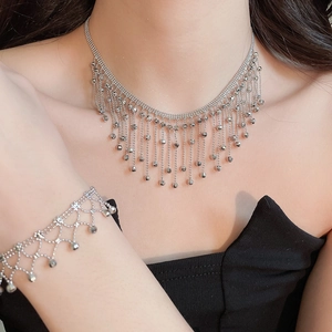 Detail of silver tassel necklace and bracelet set on a model wearing black clothing