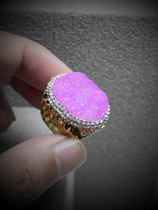 Close-up of pink gemstone ring with golden hammered metal texture and sparkling accents