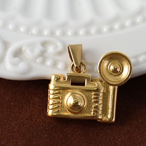 Macro shot of gold-plated stainless steel camera pendant on a soft brown velvet surface