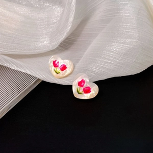 Macro detail of heart-shaped pearl studs with delicate red tulip floral patterns