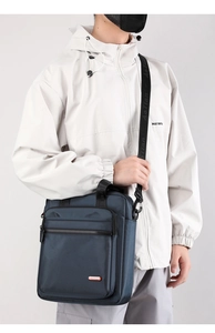 Vertical blue nylon business messenger bag shown on model for size perspective