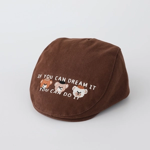 Detailed close-up of teddy bear embroidery and motivational text on a brown cotton beret