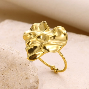 Macro shot of gold adjustable ring featuring irregular pleated texture on natural beige stone