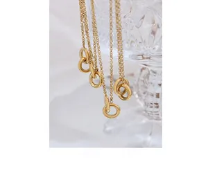 Close-up of interlocking double circle pendant on a fine gold chain over glass detail