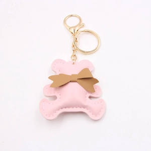 Detailed view of a pink PU leather bear keychain with a brown bow and golden hardware