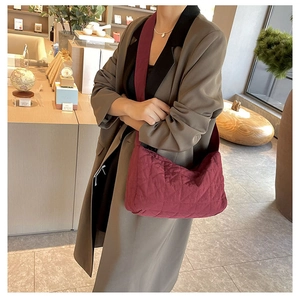 Close-up of wine red quilted hobo bag with textured fabric shown on a model