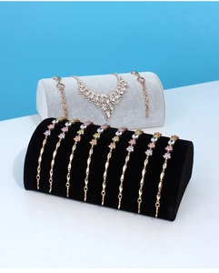 Detail of rose gold flower bracelets and teardrop necklace on velvet display stands