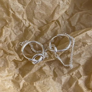 Detail of silver knot hoop earrings with delicate metal chains on brown paper