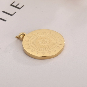 Macro shot of gold stainless steel sun totem pendant on textured beige fabric
