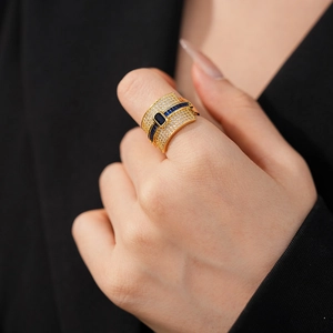 Close-up of luxury gold-plated ring with blue rectangle zircon and pavé crystals