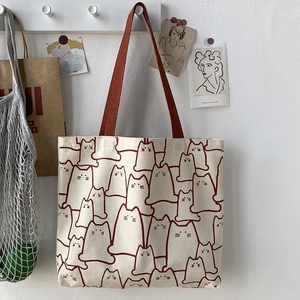 Close-up of minimalist canvas tote bag featuring cute cartoon cat patterns and brown straps