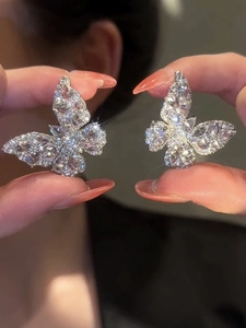 Macro shot of silver butterfly earrings with sparkling cubic zirconia held in hand