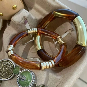 Dettaglio macro di bracciali geometrici in resina tartarugata e metallo dorato retrò