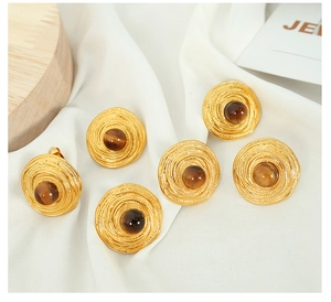 Detail of vintage gold earrings with tiger eye stone on white silk fabric background