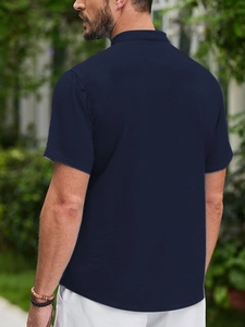 Rear view of model wearing a breathable dark blue short-sleeve polo shirt outdoors