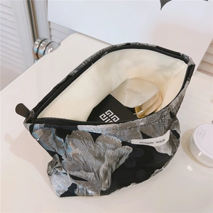Detail of the jacquard makeup bag interior showing capacity with a silver floral pattern